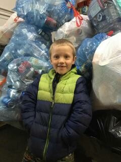 boy with pile of cans and bottles for recycle in bags